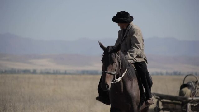 A man in a skullcap on a horse rides across the field