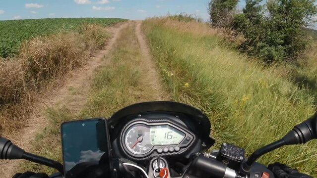 Motorcycle riding on the dirt country road to the scenic travel destination, adventure moto traveling in the summer, first person point of view, pov