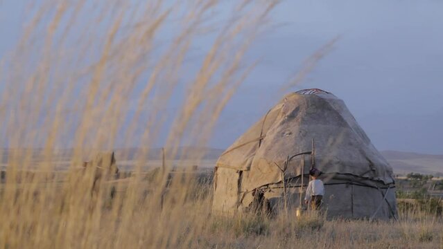 Family of nomads. Grandfather and grandson are sitting near the yurt