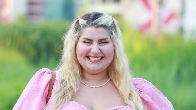 Close up portrait of happy curvy blonde young woman laughing looking at camera outdoor