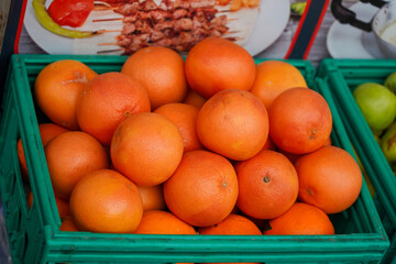 Pile of fresh oranges in a green basket for sale at a roadside grocery store. Close-up view of fresh oranges fruit.
