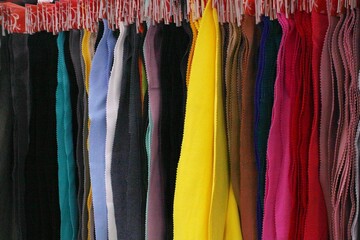 Colored textile samples of furniture and clothing upholstery of a fabric in shop. Close-up palette of texture vertical stripes on hangers. Fashion industry concept. Sewing materials. Embroidering