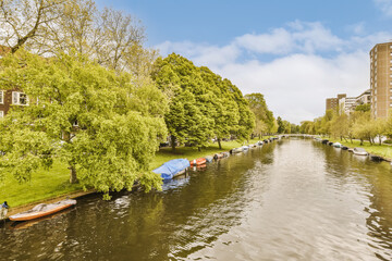 some boats in the water with buildings on either sides and trees growing along the riverbank, as seen from above