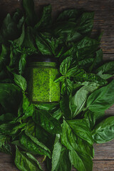 Pesto sauce in a glass jar. green basil leaves
