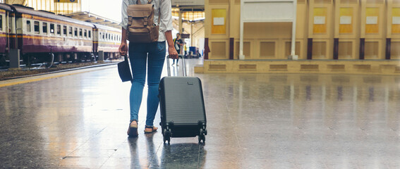 Banner of Travel concept. At train station, Young Tourist Girl walk and Dragging luggage suitcase...