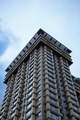 Low-angle view of modern high rise residential building. Blue sky with white clouds in the background. Modern architecture from glass and steel. Concept of real estate in Kyiv, Obolon neighborhood