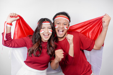 A young Asian couple with a happy successful expression wearing red top and headband while holding...