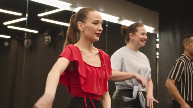 Medium slowmo of diverse cheerful young group of people dancing bachata together at dance studio