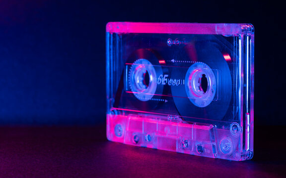Dark image of transparent cassette tape illuminated with red and blue light