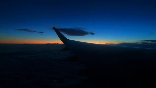 a wing of an airplane with a flashing lantern on the background of sunset in the sky
