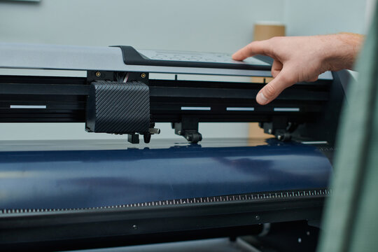 Cropped view of young craftsman using screen printing machine during process in print studio, small business owner working on project , printmaking, creative process, workflow