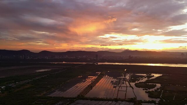 Aerial shot of Mumbai city at sunrise showing traffic , saltpans and Navi Mumbai. Stunning morning drone shot of Mumbai. Aerial Top down shot of salt pan revealing salt field. Orange sky Mumbai