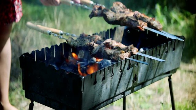 Cooking souvlaki food on picnic using metal skewers and charcoal with beef
