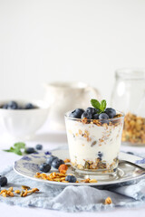 Bicchiere di yogurt con granola e mirtilli in primo piano 