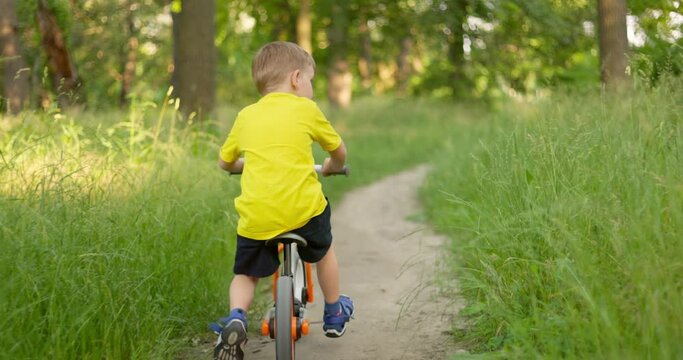 Child ride on bicycle through the forest on summertime vacations.