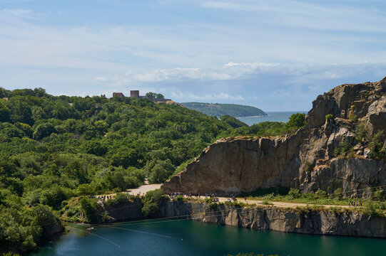 Blick auf den Granit-Steinbruch mit dem k&uuml;nstlchen See Opals&oslash;en auf der d&auml;nischen Ostseeinsel Bornholm mit der Burgruine Hammershus an einem sommerlichen Tag.