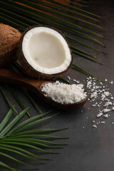 Creative image of half cut coconut and coconut flakes on a dark background