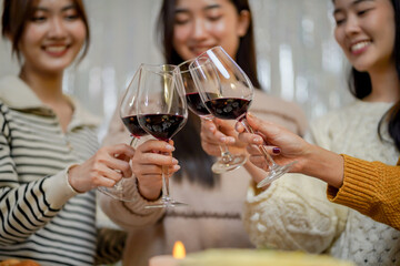 Cheerful friends enjoying home Birthday holiday party. Asian Friends cheering drinking red wine celebrating Christmas or New Year party