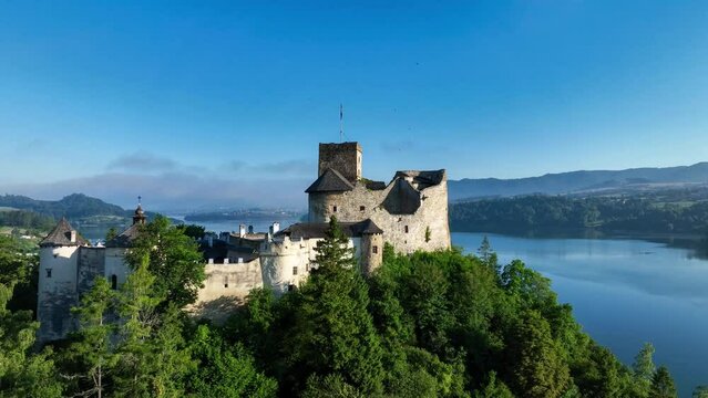 Poland. Medieval Castle in Niedzica, 14th century (upper castle), Polish or Hungarian in the Past. Artificial Czorsztyn Lake. Aerial revealing video in the morning in sunrise light