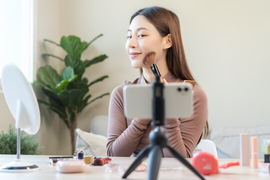 Beauty blogger, asian young woman, girl vlogger makeup face, showing, reviews cosmetics products while recording video, tutorial to share on social media. Business online influencer on smartphone.