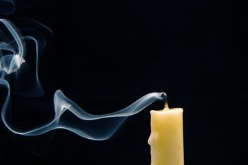 Smoke from an extinguished candle on a dark background. The concept of spirituality and the end of...