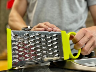 young man cooking food in the kitchen. Grater for vegetables.