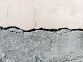 Space divided horizontally in half by deep fissure. Large long winding crack in an old plastered and painted wall. Copy space. Selective focus.