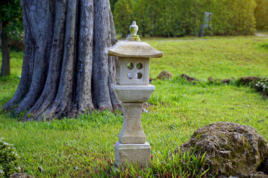 Stone lanterns in a Japanese style rock garden Placed at a distance from each other on the side of the path to see the garden. Soft and selective focus.