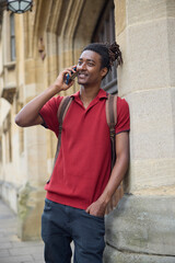 Male Student Making Call On Mobile Phone Outside University Building In Oxford UK