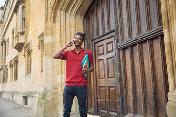 Male Student Making Call On Mobile Phone Outside University Building In Oxford UK