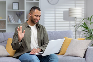 Happy and smiling young hispanic man talking remotely with his psychologist doctor, waving hand to...