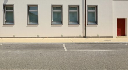 Modern building with a row of new PVC windows. Yellow concrete sidewalk and asphalt road in front....