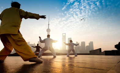 People practice taiji on the bund, oriental pearl tower in the distance,  in Shanghai, China