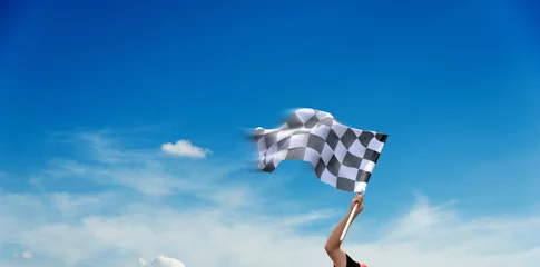 Fotobehang Formule 1 Checkered race flag in hand against blue sky  © xy