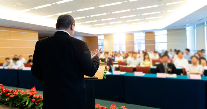 Business man making a speech in front of big audience at a conference hall