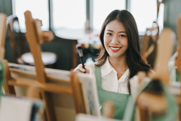 Female artist painting on canvas with brush Young painter working on the floor of her art studio creative young woman painting with oil paints creative concept