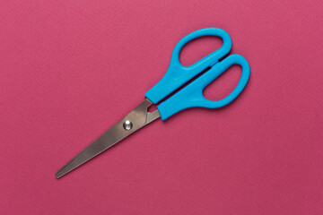 Blue scissors on color backgroung, top view