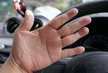 A hand on the steering wheel of a car, focus on hand.