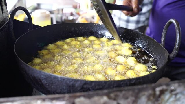Close-up sense of Making Frying Fritters Indian Street food which is also known various name like Moong Dal Pakoda, Moong Dal Bhajiya, Moong Dal Vada, Pakoda, Bhajiya, Aloo Pakora, bhajiya, etc. 