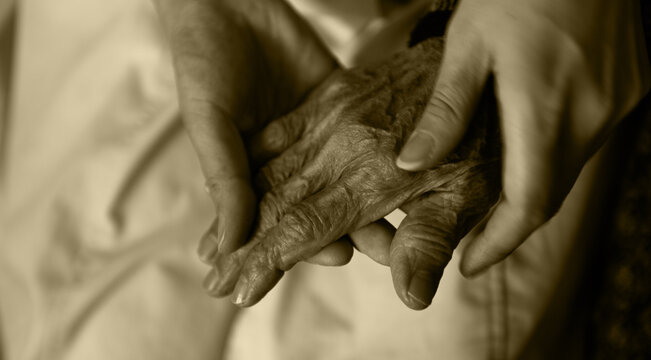 Young girl's hand holding old woman's wrinkled hands