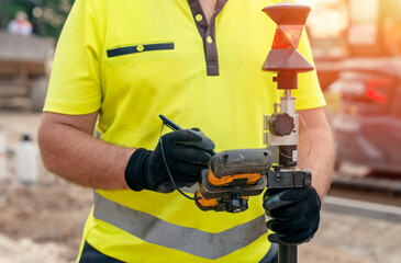 Site engineer surveyor using rugged tablet controller computer to operate EDM total station for setting out and surveying close-up