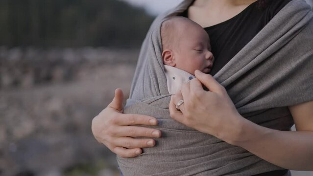 Small newborn baby boy with his mother at a park. Sunset. Slow Motion.