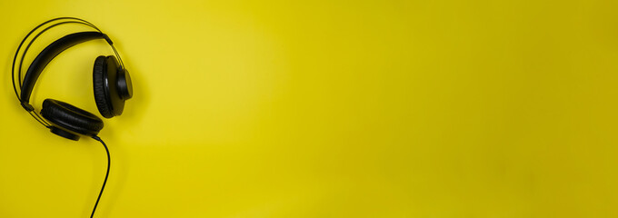 Banner, black headphones on a yellow background,top view.Headphones for playing games,listening to...