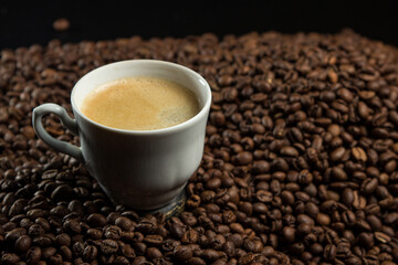 A cup of espresso coffee on a background of coffee beans.