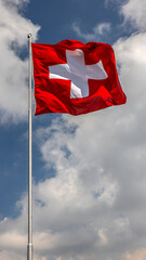die Fahne der Schweiz im Wind vor blauem Himmel