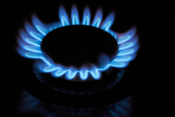 Flaming gas burner on household kitchen stove in the darkness