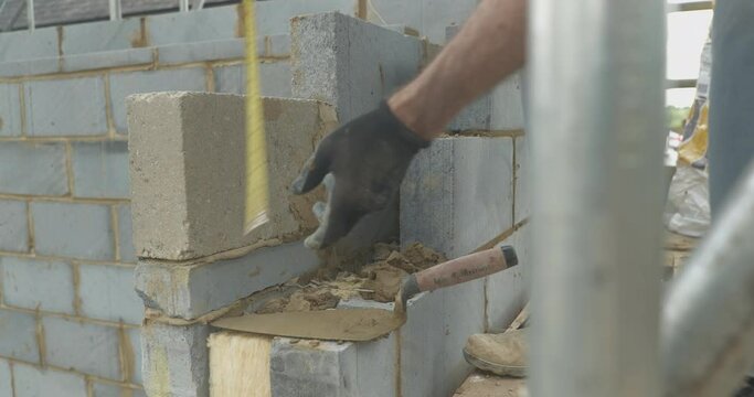 Close up of construction worker laying mortar between bricks jointing