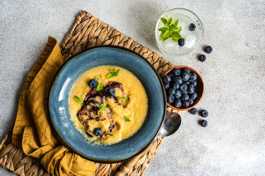 Appetizing polenta porridge with blueberries and lemonade served on table