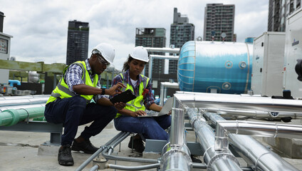 Male and Female engineer team working on the rooftop of a high building in City