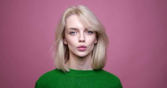 A Caucasian woman standing against a vibrant pink background. With a determined expression, she confidently utters the word No, emphasizing her disagreement.